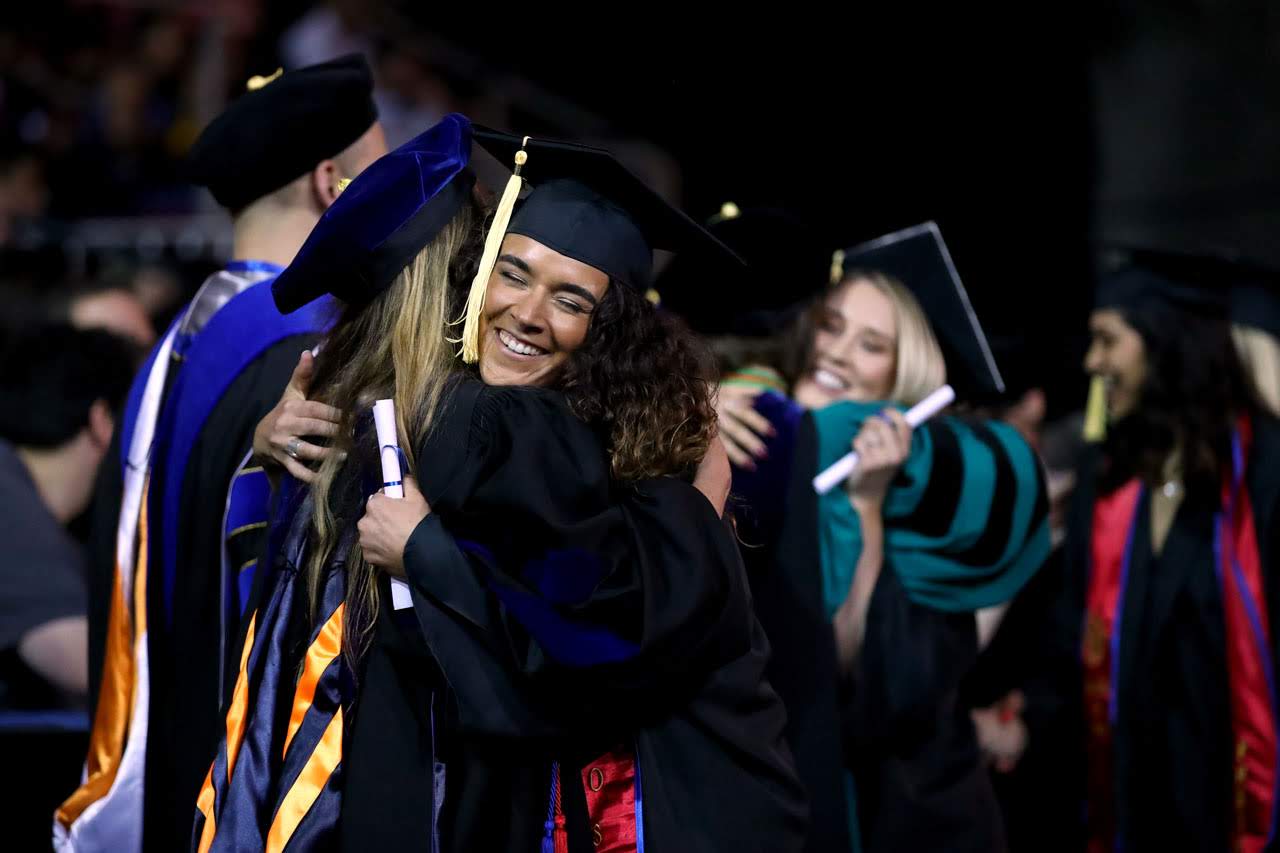 Faculty hugging students during commencement