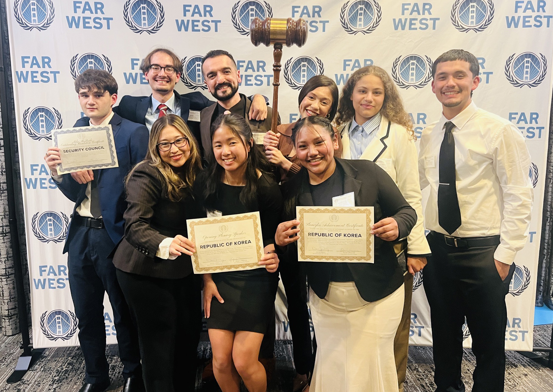 Students standing with large gavel and certificates in front of Model Un backdrop
