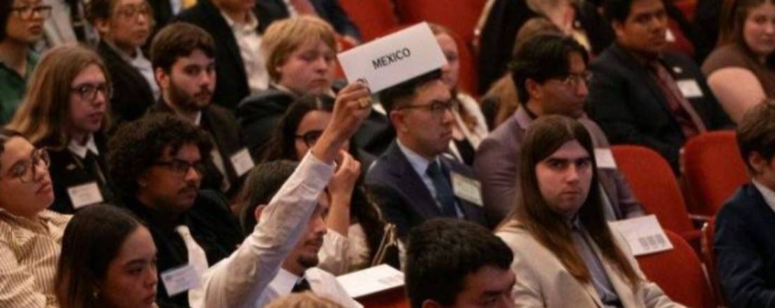 Fresno State student in auditorium holds up Mexico sign during roll call