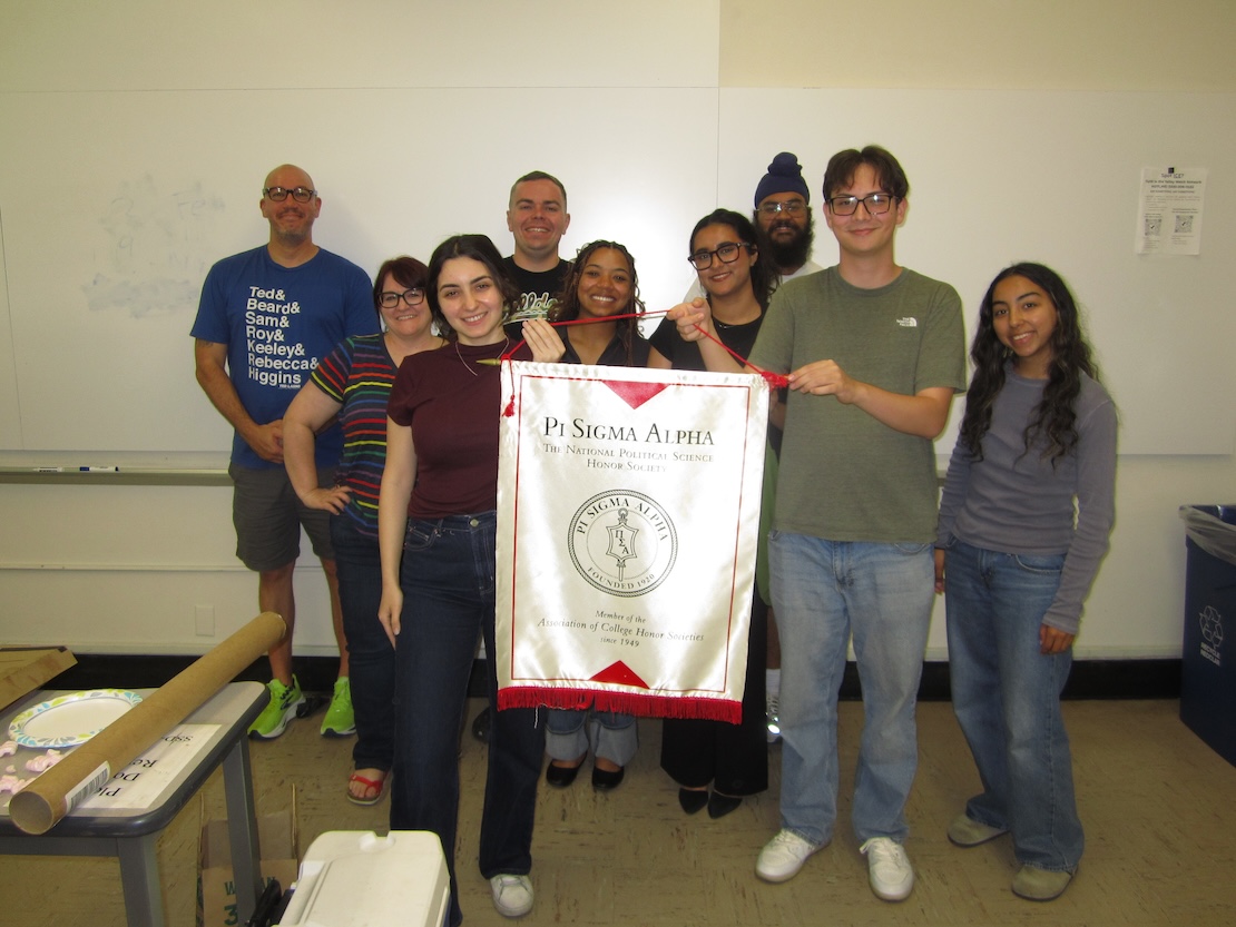 Group of pi sigma alpha students holding pi sigma alpha banner